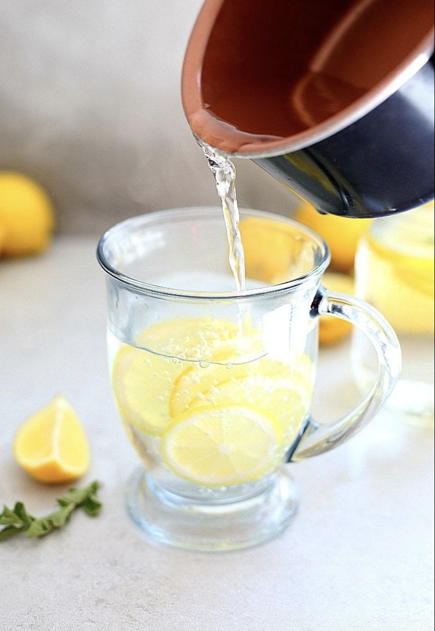 ماء دافئ مع شرائح ليمون في كوب شفاف