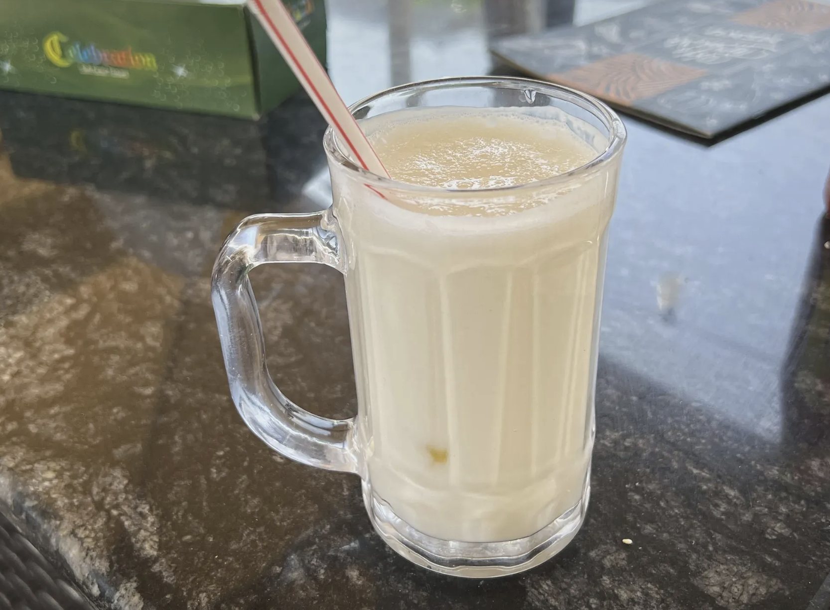 لبن مبستر سائل في كوب زجاجي شفاف على طاولة رخامية