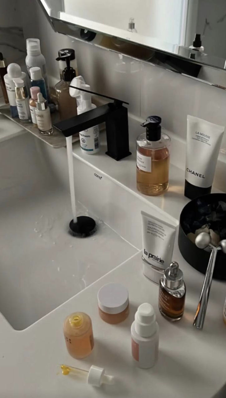 جموعة منتجات عناية بالبشرة تشمل سيروم ومرطب وغسول موضوعة على طاولة مضاءة بإضاءة ناعمة