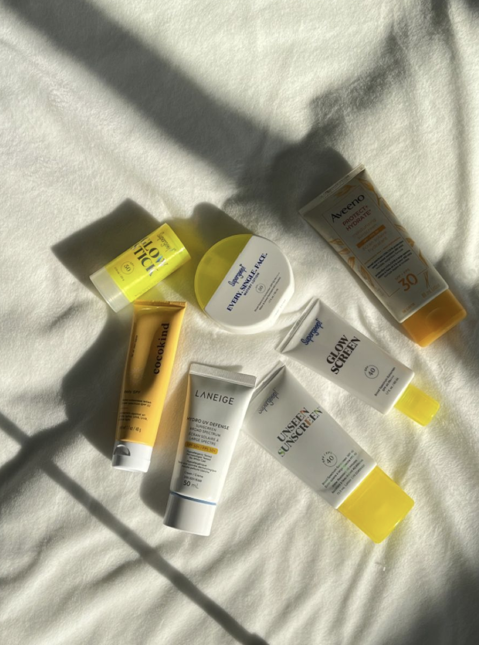 "عبوات سكين كير (سيروم وواقي شمس وكريم) مرتبة بجانب منشفة قطنية ونبات صغير."