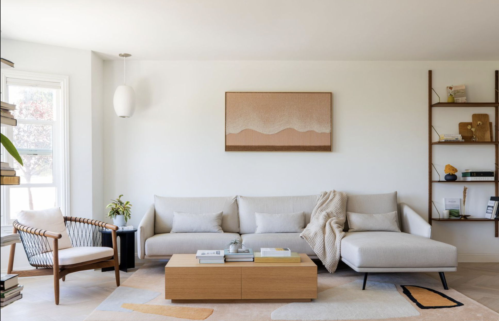 كنبة حديثة بخطوط مستقيمة وألوان حيادية داخل غرفة معيشة بسيطة بإضاءة طبيعية وطاولة قهوة خشبية