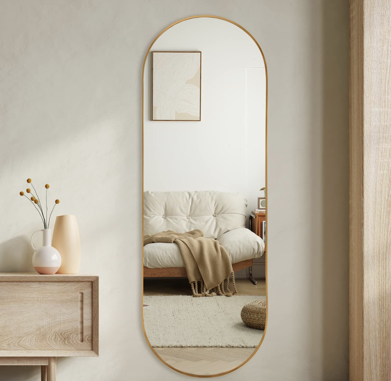 مرآة بيضاوية بحافة معدنية ذهبية رفيعة على جدار فاتح ضمن ديكور حيادي أنيق
