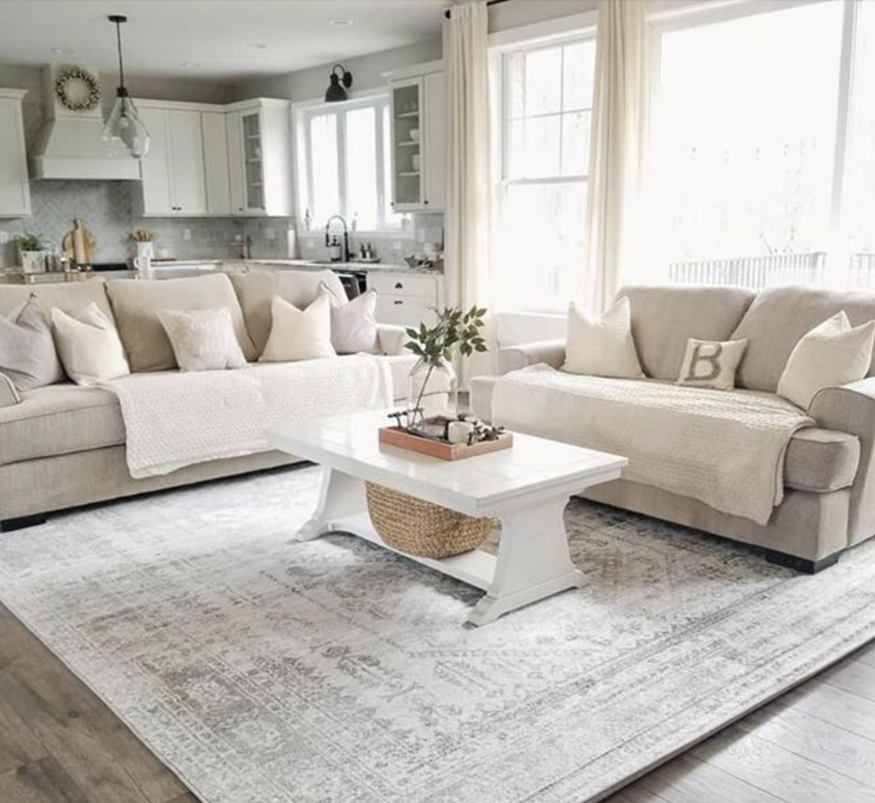 غرفة معيشة حيادية بسجادة بيج رملي ونثريات فاتحة تعطي إحساس هادئ ودافئ