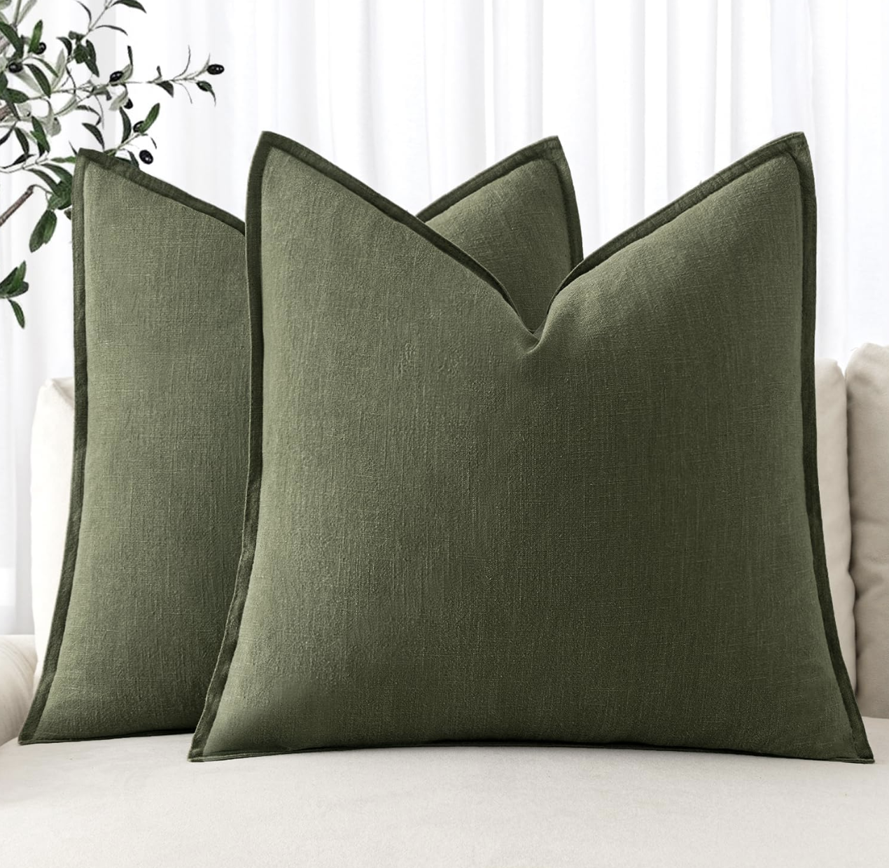 مخدات ديكور باللون الأخضر الزيتوني على كنبة فاتحة لإضافة عمق لوني هادئ.