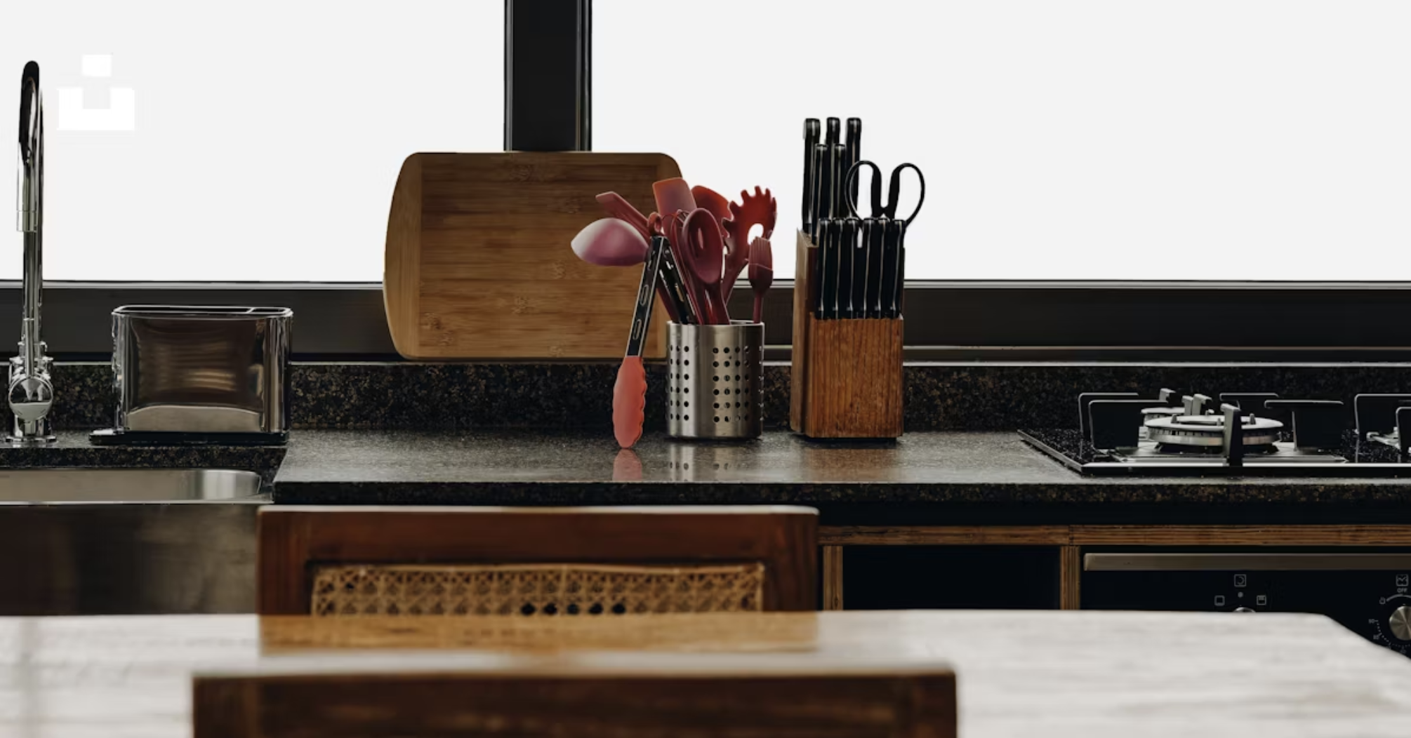 سطح رخامة بجانب منطقة الطبخ مع حامل أدوات وسكاكين وأدوات تحضير قريبة للاستخدام السريع أثناء الطبخ.