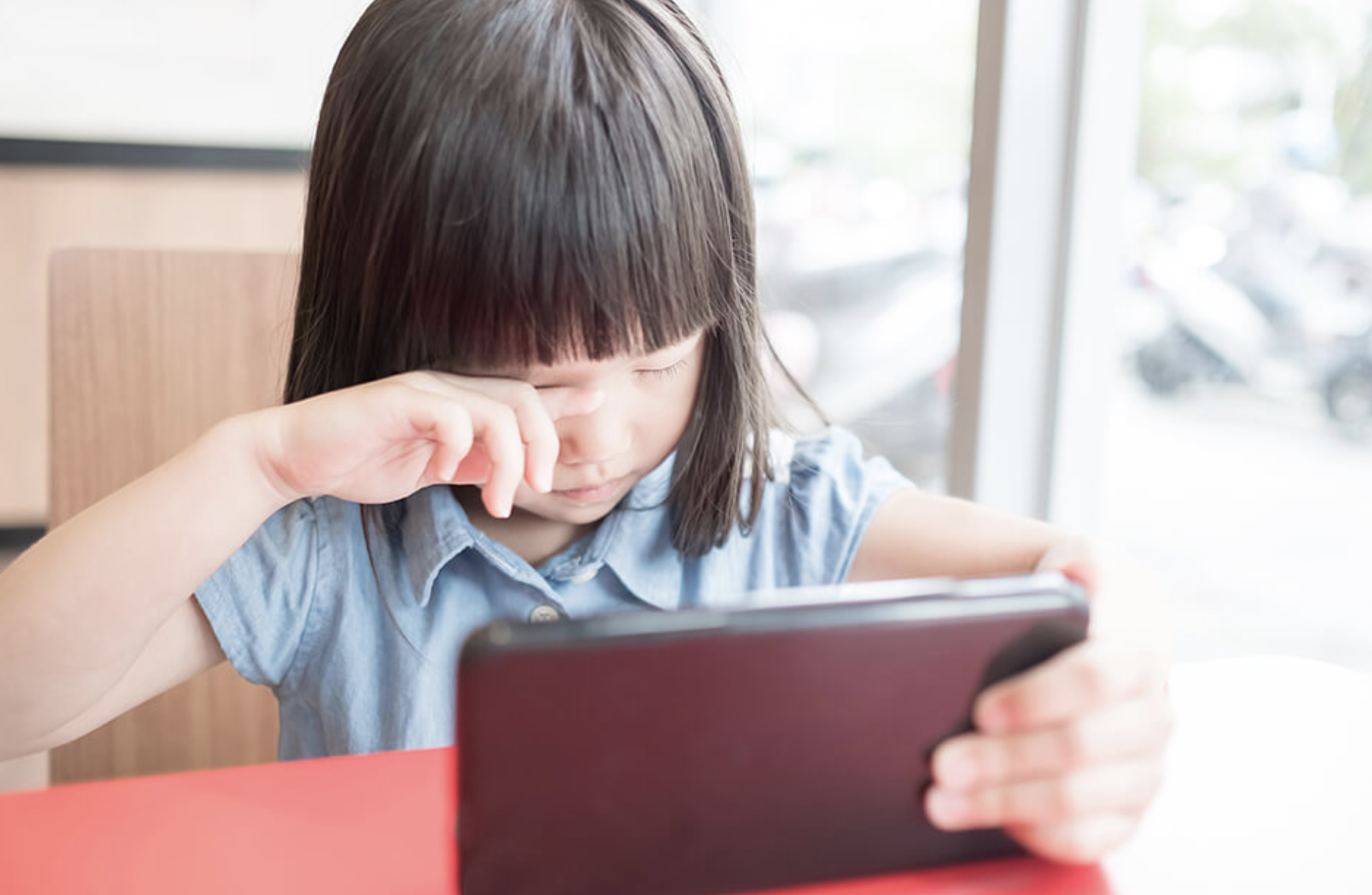 قصر النظر عند الأطفال بسبب الشاشات: فرك العين أثناء استخدام التابلت كإشارة محتملة لإجهاد العين الرقمي أو تعب التركيز القريب.